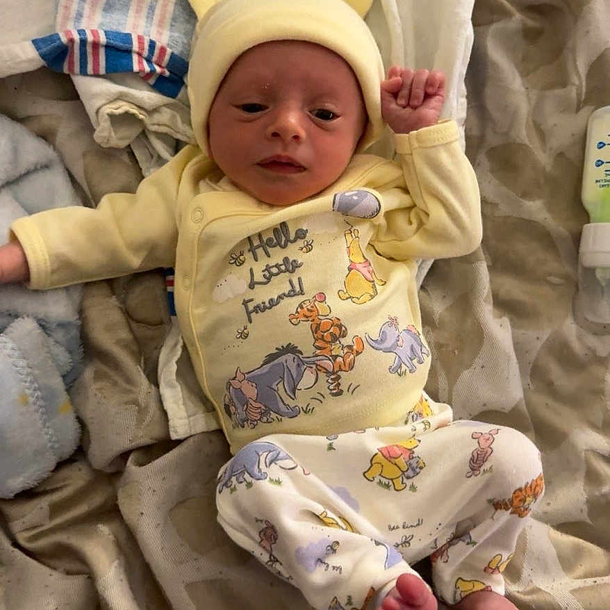 Ryan Jr joined the competition — help win amazing prizes! baby, infant, yellow_clothing, hat, blanket, patterned_blanket, foot, hand, face, lying_down, cute, newborn, soft_lighting, indoors, sleepwear, cartoon_print, toddler, baby_garments, resting, small