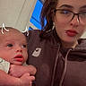 Ryan Jr is registered to the contest to win money with this photo: baby, woman, glasses, hoodie, indoor, window, blue_sky, holding, doodle, horns, portrait, face, person, child, cute, casual_clothing, young_adult, infant, skin, expression