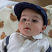 Nicolas joined the competition — help win amazing prizes! baby, child, face, cap, hat, bow_tie, shirt, suspenders, blanket, teddy_bear_pattern, infant, cute, portrait, lying_down, indoor, clothing, young_child, expression, closeup, headwear