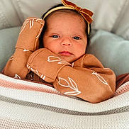Zarajade is registered to the contest to win money with this photo: baby, infant, blanket, knit, brown_clothing, headband, bow, face, eyes, hands, cozy, soft_lighting, portrait, indoor, cute, newborn, child, calm, closeup, patterned_clothing