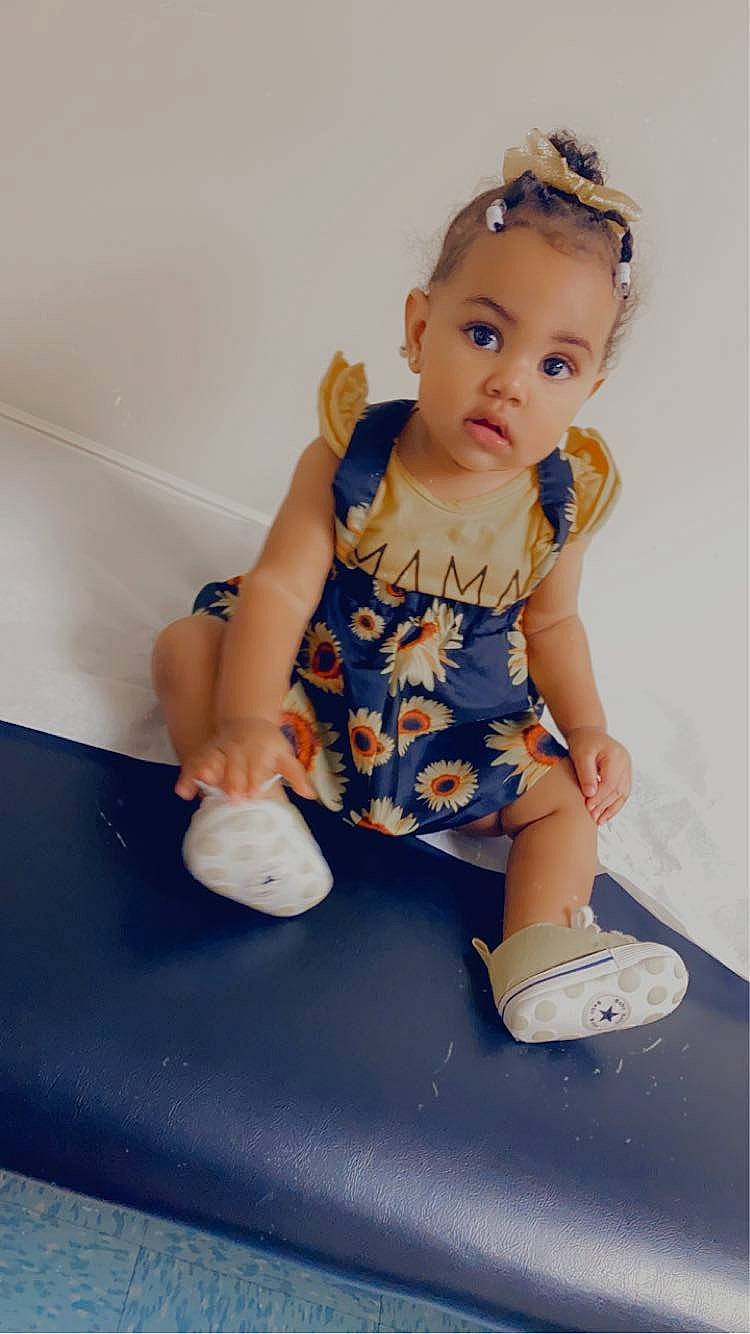 Sade is registered to the contest to win money with this photo: baby, baby_toddler_clothing, blond, child, dress, electric_blue, eye, face, fashion_accessory, foot, hairstyle, human_leg, jewellery, joint, knee, pattern, person, sitting, sleeve, thigh