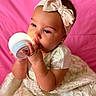 Lailah is registered to the contest to win money with this photo: baby, child, headband, bow, dress, elegant, glowing_object, hand, pink_background, portrait, cute, infant, face, curious, soft_lighting, indoors, small_earrings, closeup, sitting, adorable
