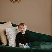 Oaklee joined the competition — help win amazing prizes! baby, child, smile, couch, pillow, mirror, indoor, cozy, portrait, cute, clothing, socks, seated, home, decor, young, infant, furniture, expression, relaxed