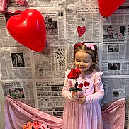 Calista joined the competition — help win amazing prizes! child, girl, toddler, rose, heart_balloon, balloon, pink_dress, hair_bow, valentines_decor, newspaper_backdrop, holding, smiling, standing, portrait, shoes, holiday_decor, fabric_drape, heart_shape, playful, cute