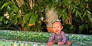 Maria participe au concours pour gagner de l'argent avec cette photo : baby, child, colorful, cute, face, fun, greenery, happy, nature, outdoor, pigtails, plants, pool, portrait, sitting, smiling, sunlight, tiled_pool, tropical, water