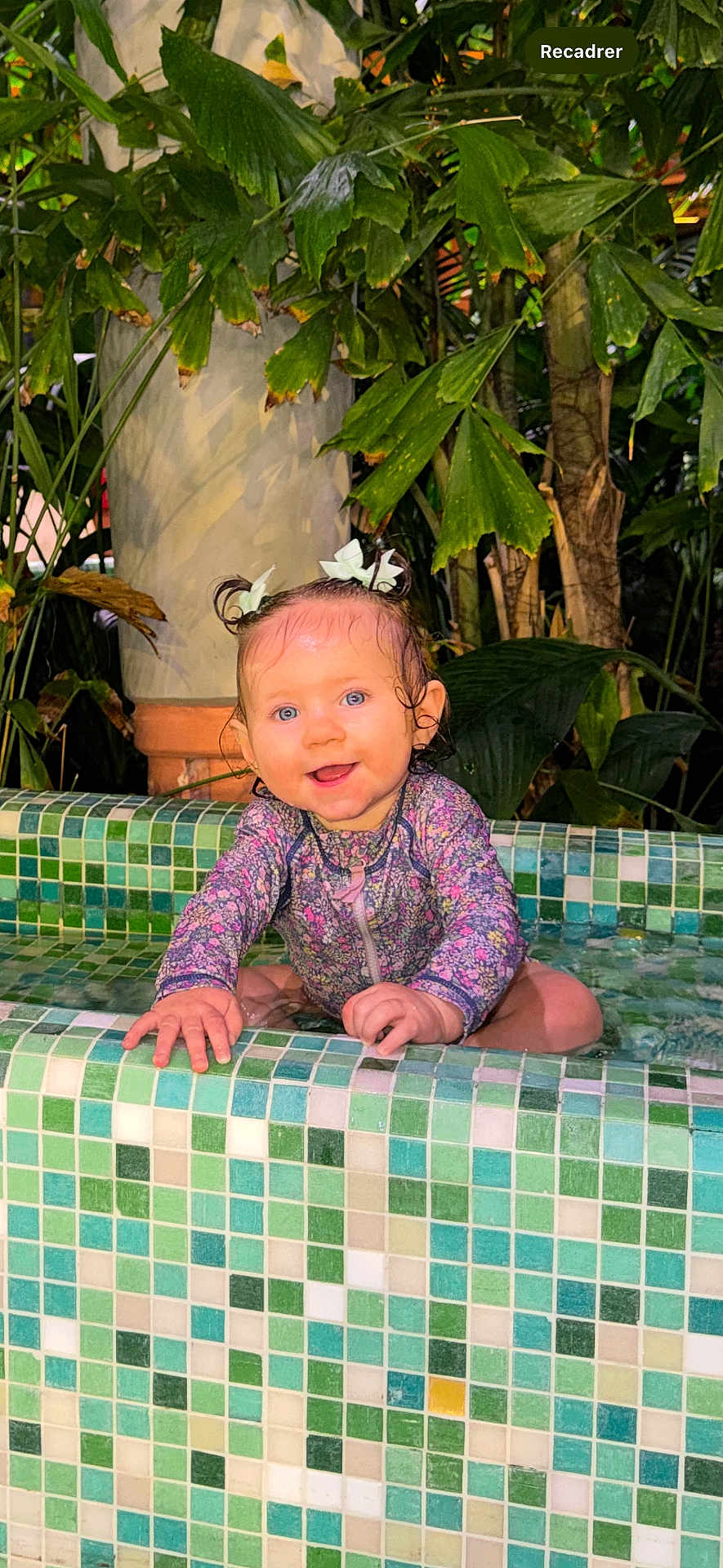 Maria participe au concours pour gagner de l'argent avec cette photo : baby, child, smiling, pool, water, wet_hair, pigtails, floral_swimsuit, greenery, plants, tiles, mosaic, outdoor, nature, happy, cute, portrait, sitting, playful, summer