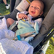 Loan participe au concours pour gagner de l'argent avec cette photo : baby, stroller, blanket, smiling, outdoor, grass, person, toy, child, clothing, seatbelt, sunlight, happy, infant, face, hand, fabric, footwear, leg, casual