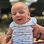 Loan a rejoint le concours — aidez-le/la à gagner de superbes lots ! baby, infant, smile, happy, person, onesie, patterned_clothing, hand, holding, portrait, close_up, child, cute, outdoor, blurred_background, people, skin, head, face, expression