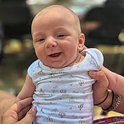 Léa a rejoint le concours — aidez-le/la à gagner de superbes lots ! baby, infant, smile, happy, person, onesie, patterned_clothing, hand, holding, portrait, close_up, child, cute, outdoor, blurred_background, people, skin, head, face, expression