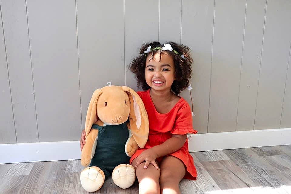 Leilani joined the competition — help win amazing prizes! abdomen, child, companion_dog, floor, flooring, foot, football, happy, hardwood, headwear, human_body, human_leg, jewellery, joy, knee, person, smile, sportswear, t_shirt, teddy_bear