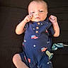 baby, infant, onesie, clothing, blue, flag, american_flag, pattern, fist, hand, face, skin, person, lying_down, bed, blanket, newborn, cute, small, indoor