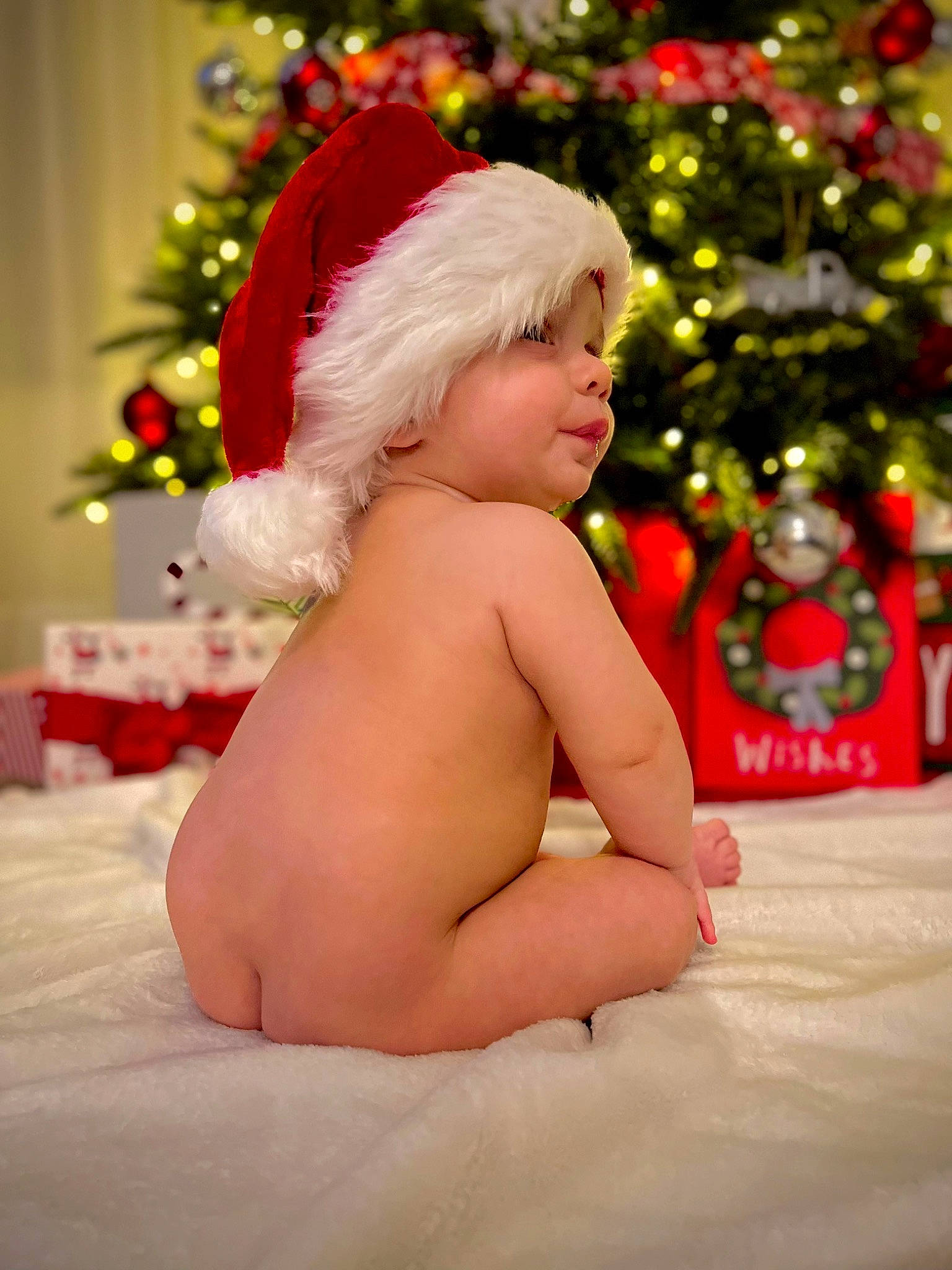 Landen is registered to the contest to win money with this photo: baby, child, christmas, christmas_decoration, christmas_ornament, christmas_tree, event, fun, happy, hat, headwear, holiday, holiday_ornament, human_body, lap, ornament, person, plant, santa_claus, smile