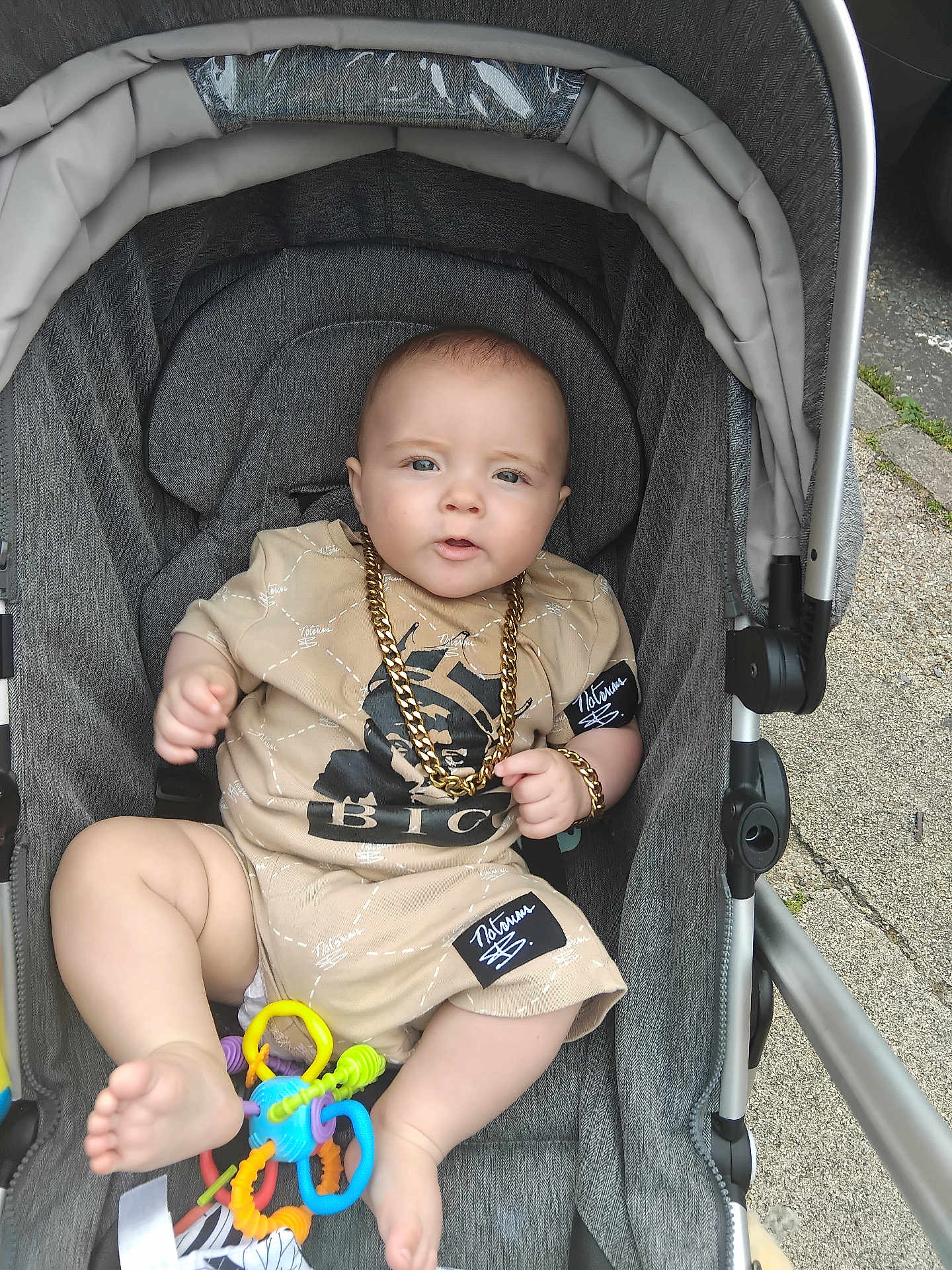 Grayson-Jo joined the competition — help win amazing prizes! baby, stroller, child, gold_chain, toy, beige_clothing, outdoor, footwear, expression, person, infant, sitting, accessory, cute, casual, street, play, hand, foot, portrait