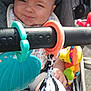 baby, child, stroller, cap, bib, toy, colorful_toy, cloth, hand, seat, comfort, infant, cute, striped_cap, outdoor, sunlight, smile, face, baby_boy, playtime