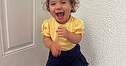 Sofia joined the competition — help win amazing prizes! toddler, child, laughing, yellow_top, navy_skirt, white_sandals, indoor, wood_floor, textured_wall, white_door, happy, cute, smiling, standing, girl, hair_buns, person, clothing, casual, portrait