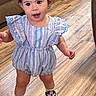 Sofia joined the competition — help win amazing prizes! toddler, child, indoor, wooden_floor, striped_romper, blue_shoes, pink_socks, hair_buns, curly_hair, walking, cute, exploring, furniture, living_room, couch, smiling, person, flooring, home, young_child