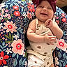 Gracelyn is registered to the contest to win money with this photo: baby, smiling, headband, bow, romper, flower_pattern, cushion, floral, happy, infant, cute, indoor, child, joyful, sitting, plush, colorful, comfort, person, portrait