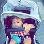 baby, barefoot, blue_eyes, bottle, casual, child, curious, curly_hair, foot, grip, hand, outdoor, red_and_white_outfit, seat, sidewalk, stroller, sunlight, toddler, urban, walking