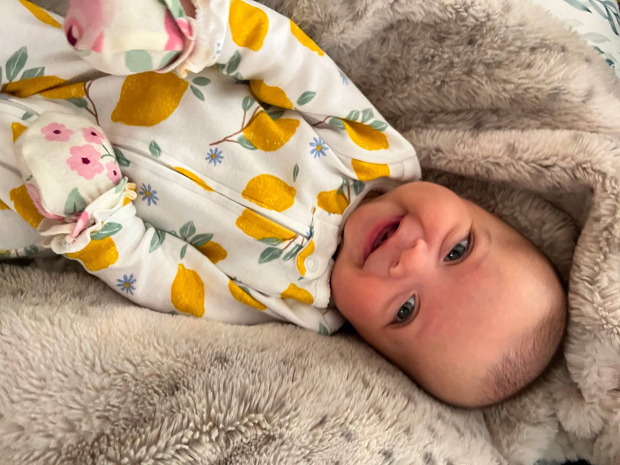 Emmie is registered to the contest to win money with this photo: baby, baby_toddler_clothing, cheek, child, comfort, eyelash, facial_expression, flooring, fur, grass, happy, human_body, joy, linens, mammal, person, plant, product, textile, toddler