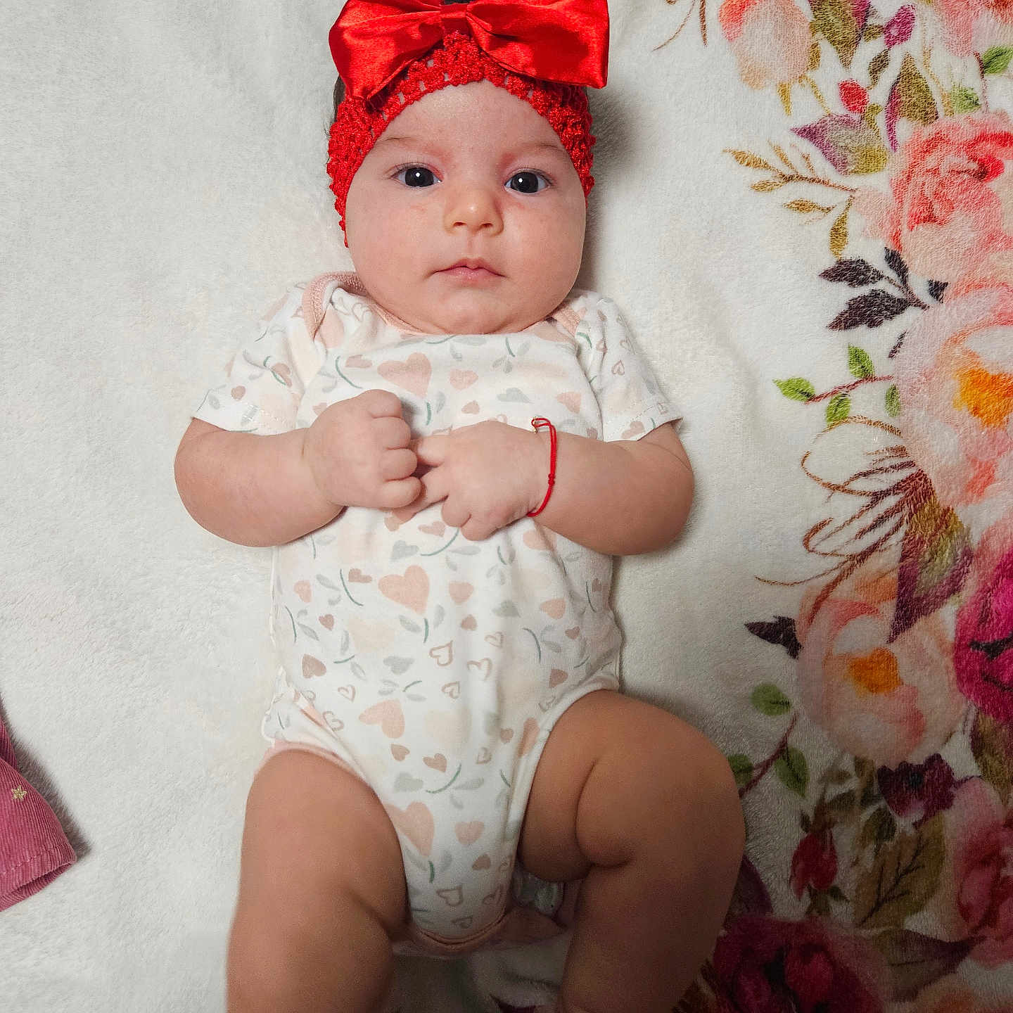 Annelisse joined the competition — help win amazing prizes! adorable, baby, blanket, child, cute, expression, fist, floral_pattern, headband, heart_pattern, indoors, infant, lying_down, newborn, onesie, person, portrait, red_bow, skin, soft_texture