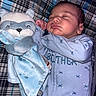 Ali is registered to the contest to win money with this photo: baby, sleeping, plush_toy, racoon, blue_onesie, infant, cozy, blanket, plaid, soft_toy, cute, peaceful, child, nap, indoors, face, hand, newborn, bed, comfort
