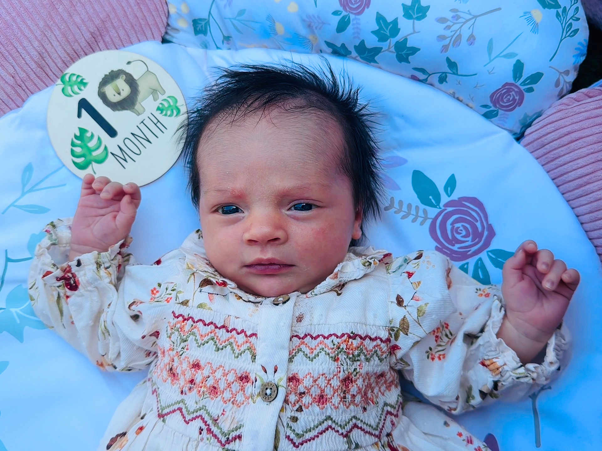 Heidi joined the competition — help win amazing prizes! baby, newborn, one_month, infant, face, hands, clothing, floral_pattern, blanket, sign, lion, portrait, cute, lying_down, indoor, child, person, closeup, soft_lighting, milestone