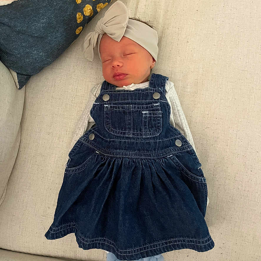 Scotti joined the competition — help win amazing prizes! baby, bow, child, clothing, couch, cozy, cute, denim_dress, fabric, headband, home, indoors, infant, peaceful, pillow, portrait, resting, sleeping, soft, toddler