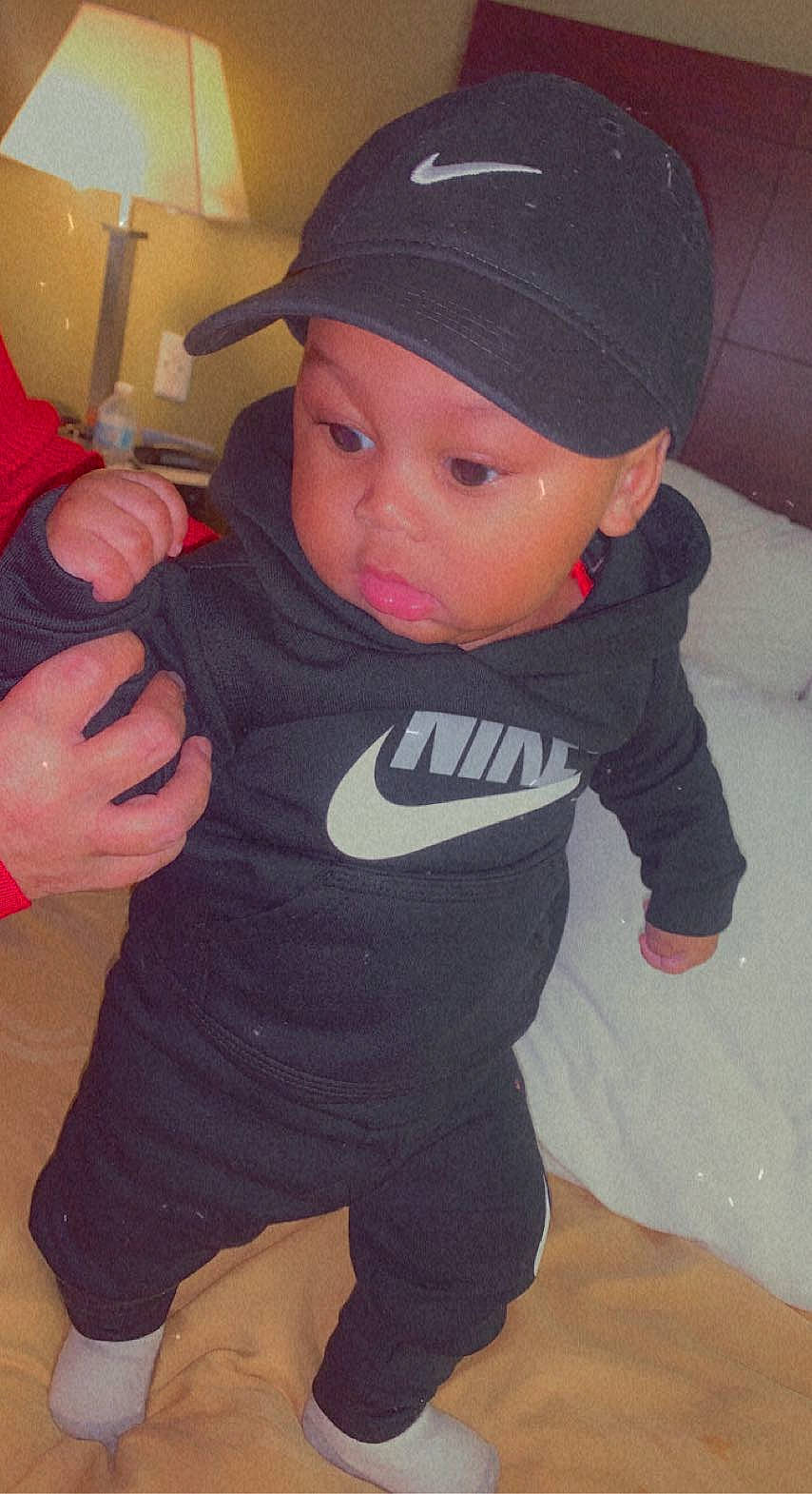 Kyree is registered to the contest to win money with this photo: arm, baby, baby_toddler_clothing, baseball_cap, cap, cheek, child, finger, fun, gesture, hand, headgear, headwear, outerwear, person, personal_protective_equipment, skin, sleeve, t_shirt, thigh