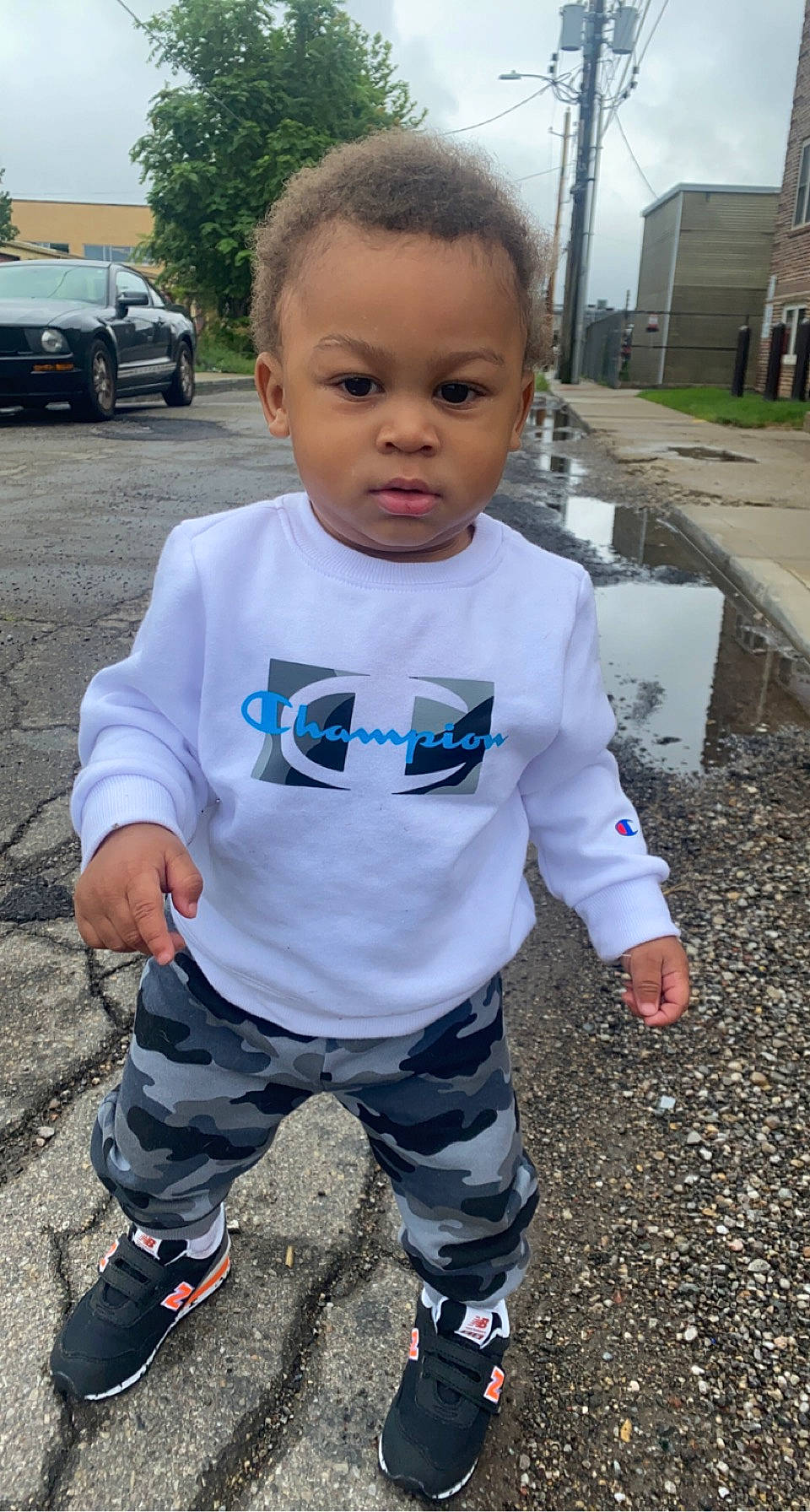 Kyree is registered to the contest to win money with this photo: asphalt, baby_toddler_clothing, black, cool, electric_blue, fun, grass, hairstyle, mouth, person, personal_protective_equipment, photograph, plant, sky, sleeve, standing, t_shirt, tire, toddler, tree