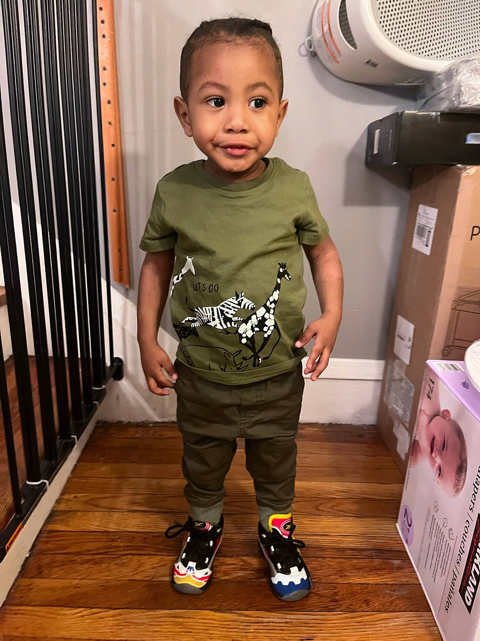 Bryce joined the competition — help win amazing prizes! baby_toddler_clothing, child, floor, flooring, footwear, hairstyle, hardwood, joint, output_device, person, product, room, sleeve, standing, t_shirt, thigh, toddler, waist, white, wood