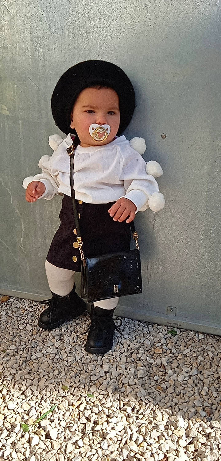 Djalya a rejoint le concours — aidez-le/la à gagner de superbes lots ! baby_toddler_clothing, boot, clothing, costume, costume_hat, doll, face, fashion_accessory, formal_wear, hat, headgear, helmet, human_body, jacket, pattern, person, sitting, sleeve, sun_hat, toddler