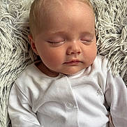 Gracie-Mae is registered to the contest to win money with this photo: baby, sleeping, infant, onesie, white_clothing, blanket, soft_texture, face, peaceful, closeup, child, newborn, cute, relaxing, portrait, indoors, resting, small_person, calm, skin