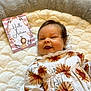 baby, infant, smiling, flower_pattern, outfit, blanket, soft_texture, card, autumn, lion_illustration, text, indoor, carpet, cute, child, happy, portrait, lying_down, cozy, warm_colors