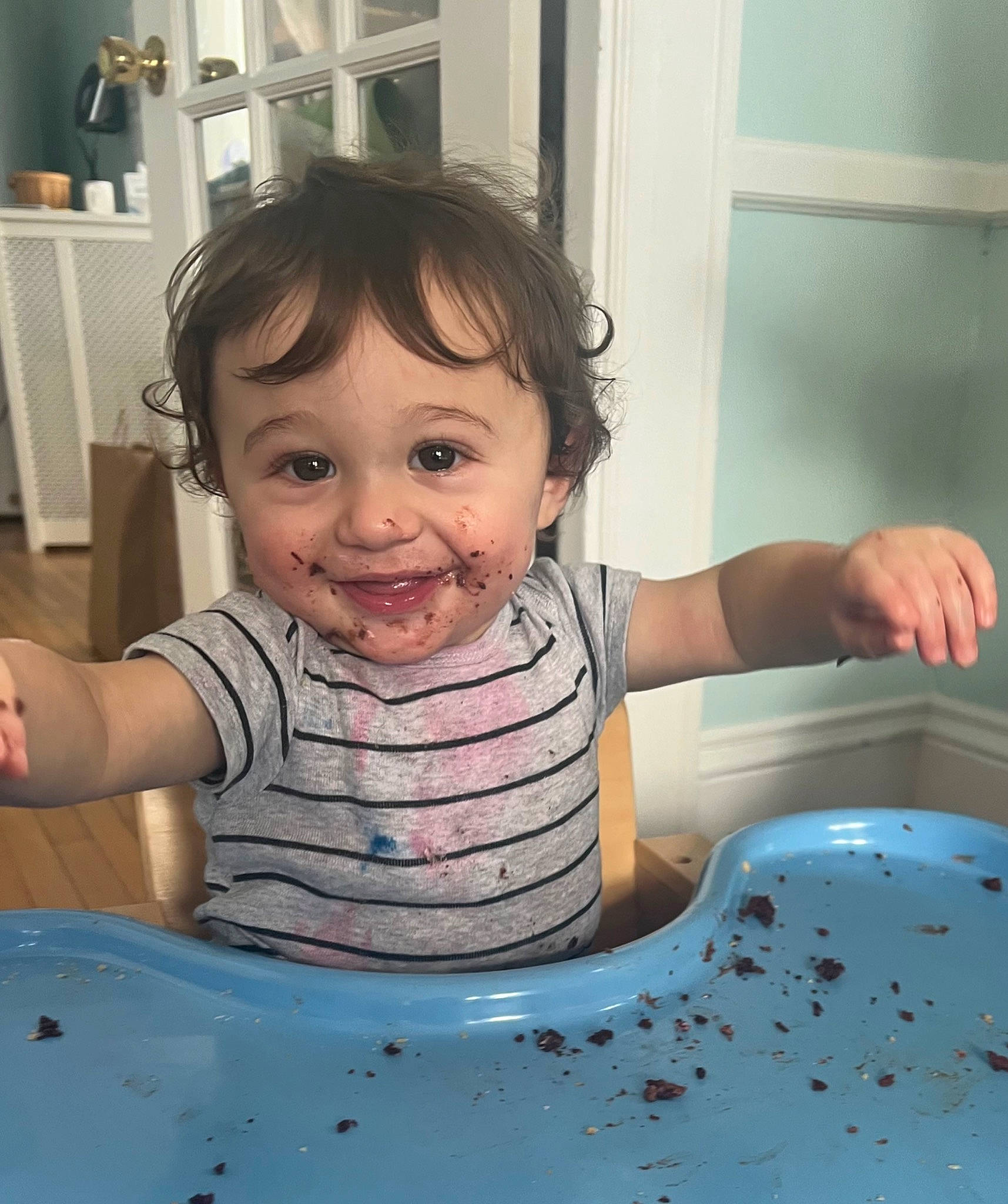 Evan is registered to the contest to win money with this photo: arm, baby_toddler_clothing, cheek, eye, facial_expression, finger, gesture, hand, happy, head, iris, joy, person, skin, sleeve, smile, standing, t_shirt, table, tableware