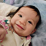 Savahnluv is registered to the contest to win money with this photo: baby, smiling, face, infant, blanket, floral_clothing, cute, lying_down, portrait, child, soft_texture, happy, indoors, young_child, person, closeup, cozy, warm, bed, sleepwear