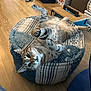cat, tabby_cat, pet, indoor, pouf, wooden_floor, playful, curious, feline, animal, resting, cozy, home, fur, whiskers, paws, looking, relaxed, striped, cute