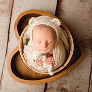 éthan participe au concours pour gagner de l'argent avec cette photo : newborn, baby, sleeping, wrapped, hat, bear_ears, stuffed_animal, heart_shaped_bowl, wooden_floor, soft_texture, cute, peaceful, infant, portrait, indoors, cozy, hands, face, child, resting