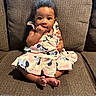 Adoree is registered to the contest to win money with this photo: baby, child, dress, sitting, couch, indoor, cute, portrait, person, furniture, pattern, clothing, feet, hand, face, smiling, curious, young, infant, adorable