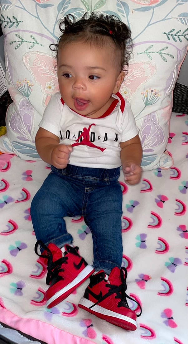 Alani is registered to the contest to win money with this photo: baby, baby_toddler_clothing, cheek, child, cool, electric_blue, eye, fun, happy, linens, pattern, person, pink, red, sitting, skin, sleeve, smile, t_shirt, toddler