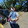 adult, american_flag, blue_sky, car, casual_clothing, child, cute, daylight, denim, denim_jacket, family, headband, holding, outdoor, parent, parking_lot, shadow, stroller, trees, white_shoes