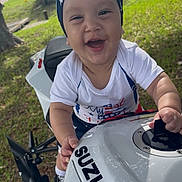 Matías joined the competition — help win amazing prizes! baby, child, smiling, headband, shirt, motorcycle, suzuki, outdoor, grass, tree, road, happy, hands, vehicle, toy, person, daylight, nature, helmet, playful