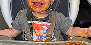 Jaxon is registered to the contest to win money with this photo: toddler, high_chair, messy, spaghetti, food, face_paint, smile, child, meal, tray, clothing, hair, indoor, happy, mess, person, seat, playful, kitchen, eating
