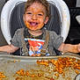 toddler, high_chair, messy, spaghetti, food, face_paint, smile, child, meal, tray, clothing, hair, indoor, happy, mess, person, seat, playful, kitchen, eating
