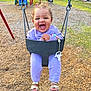 toddler, child, swing, playground, purple_clothing, unicorn_pattern, smiling, happy, outdoor, play, sand, grass, footwear, sandals, chain, park, daylight, person, toy, fun