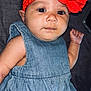 baby, black_hair, child, closeup, clothing, cute, denim_dress, fabric_background, face, fist, flower, headband, indoors, infant, lying_down, person, portrait, red_flower, skin, young