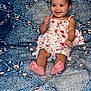 baby, barefoot, blue_pattern, child, couch, cute, expression, floral_dress, furniture, girl, happy, head, indoors, infant, person, portrait, red_bow, seated, skin, smiling