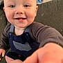 George is registered to the contest to win money with this photo: baby, child, smiling, face, hand, couch, clothing, indoor, person, blue_eyes, overalls, long_sleeve, happy, cute, infant, portrait, sitting, skin, closeup, expression