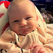 Riley joined the competition — help win amazing prizes! baby, infant, smile, face, hands, onesie, cozy, blanket, closeup, indoors, child, cute, soft_lighting, portrait, happy, newborn, skin, head, expression, warm