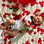 baby, infant, smiling, rose, rose_petals, balloon, heart_balloon, blanket, bow_tie, onesie, lipstick_mark, printed_photo, portrait, lying_down, playful, red_color, white_blanket, hands, feet, scattered_petals