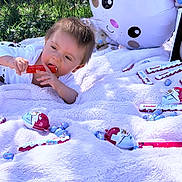 Isaak a rejoint le concours — aidez-le/la à gagner de superbes lots ! baby, blanket, candy, child, chocolate, cute, easter, egg, grass, inflatable, kinder, lying, outdoor, person, play, plush, red, smiling, toy, white